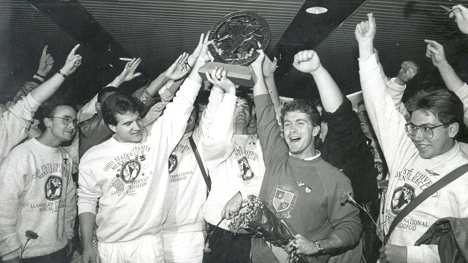 In 1990, the Men’s Glee Club competed at the Llangollen International Musical Eisteddfod where they won the male chorus division, then won the overall competition unanimously as voted by nine judges from eight different countries.