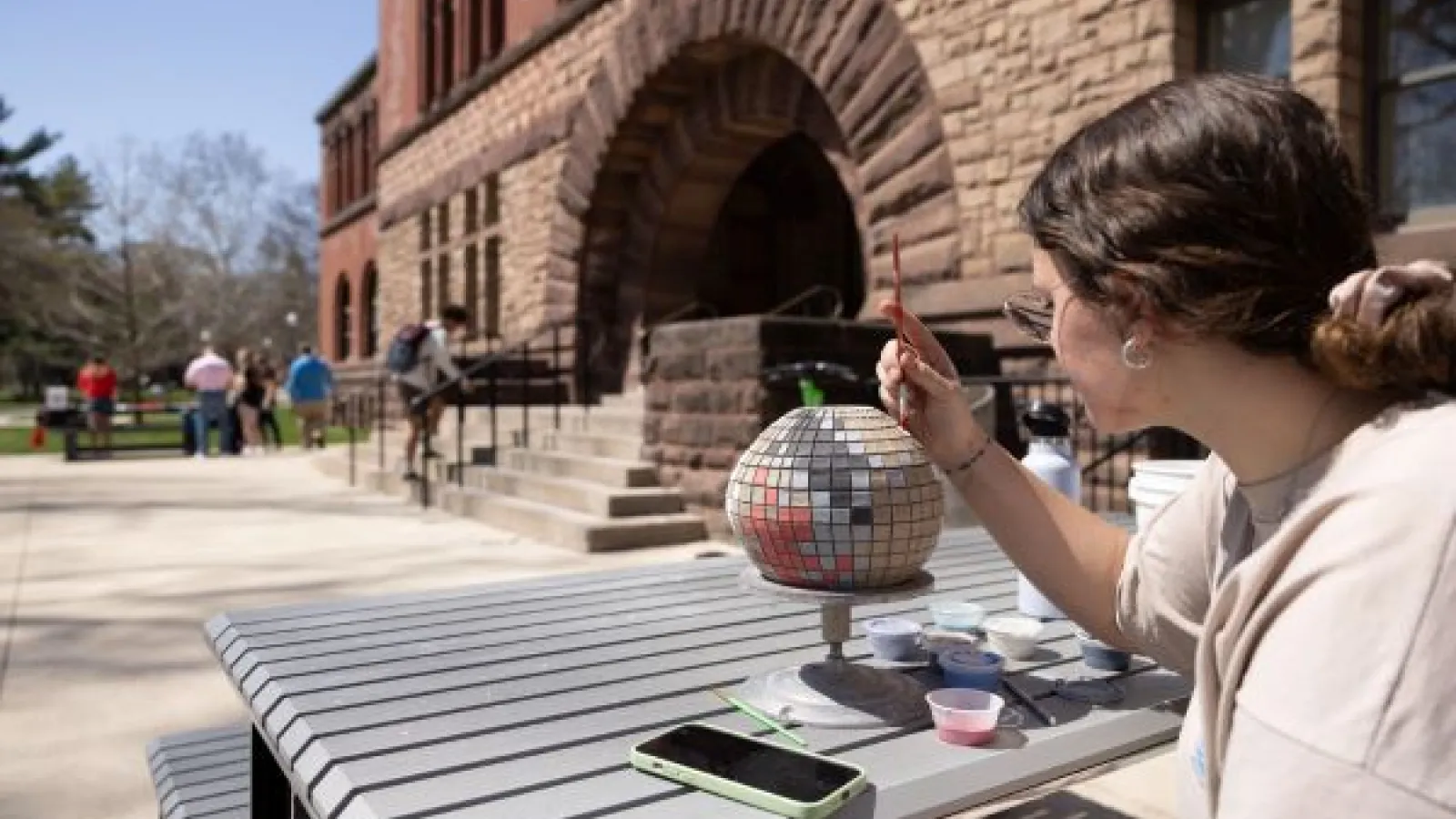 a student paints a sculpture in front of the Hayes Hall steps
