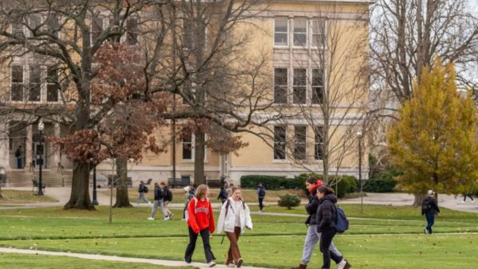 students walk past Mendenhall Lab, a yellow stone building
