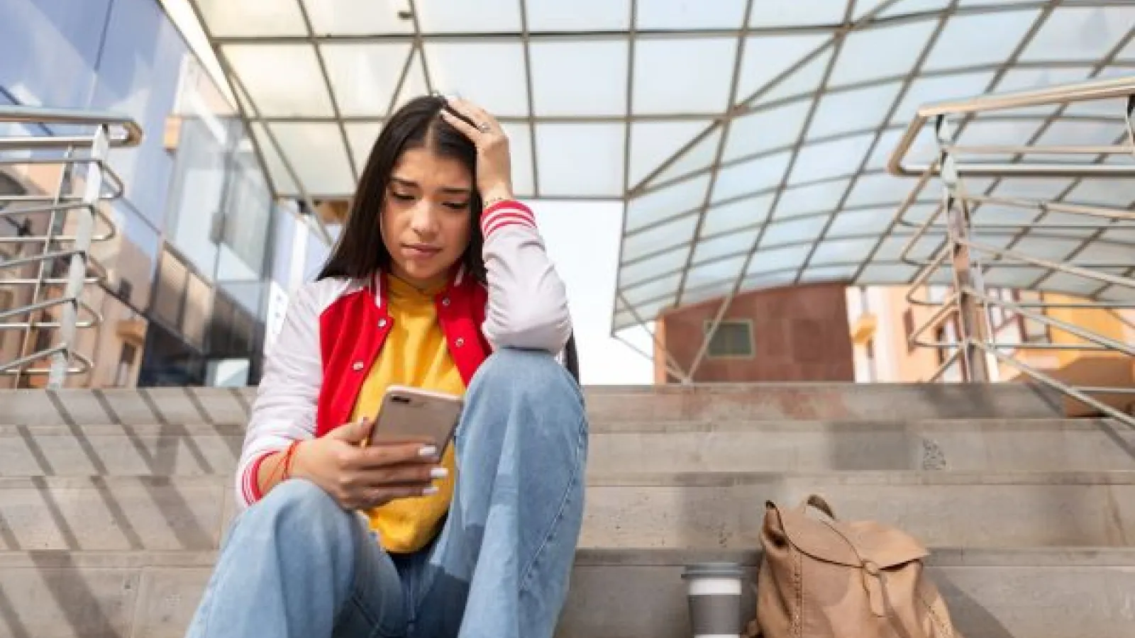 a young woman with dark hair looks sadly at her phone