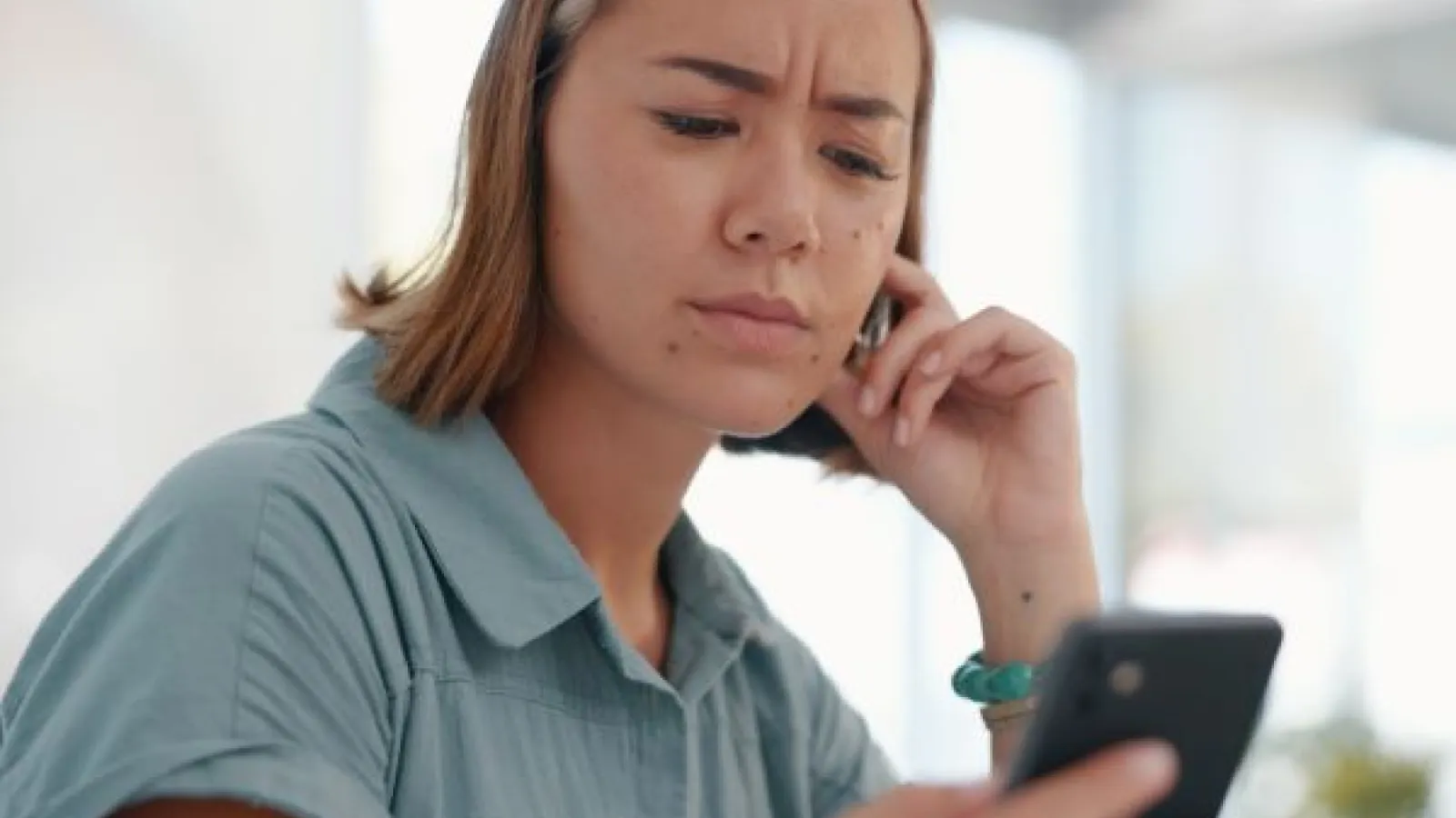 a confused woman looks at her phone