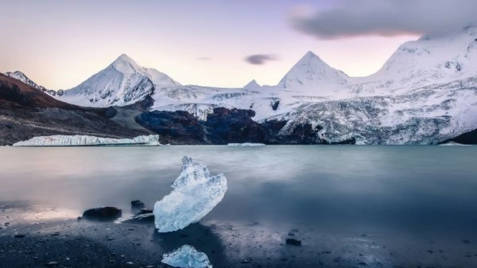 a lake in front of snowy mountains and glaciers