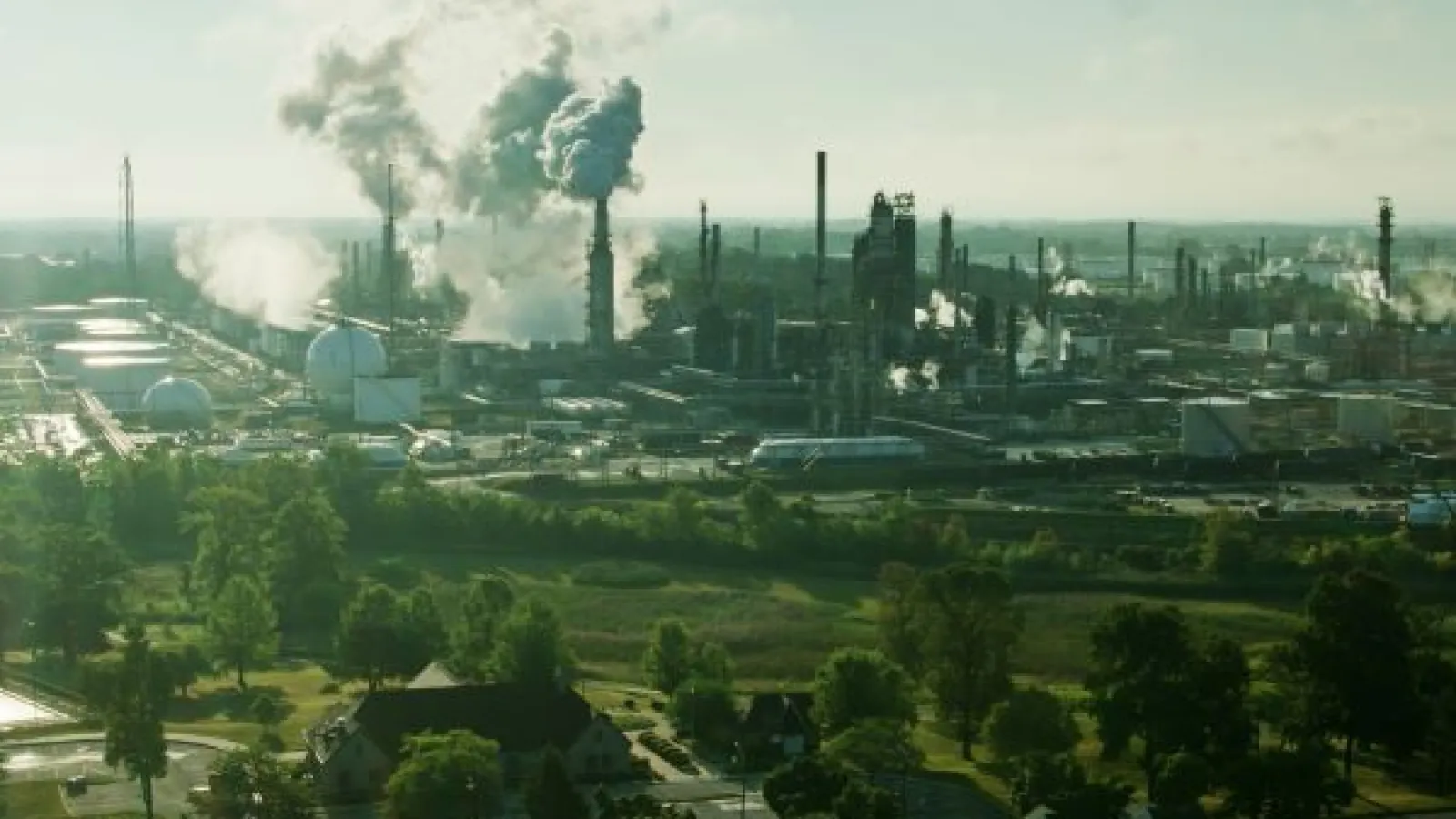 an oil refinery in the background of a city neighborhood