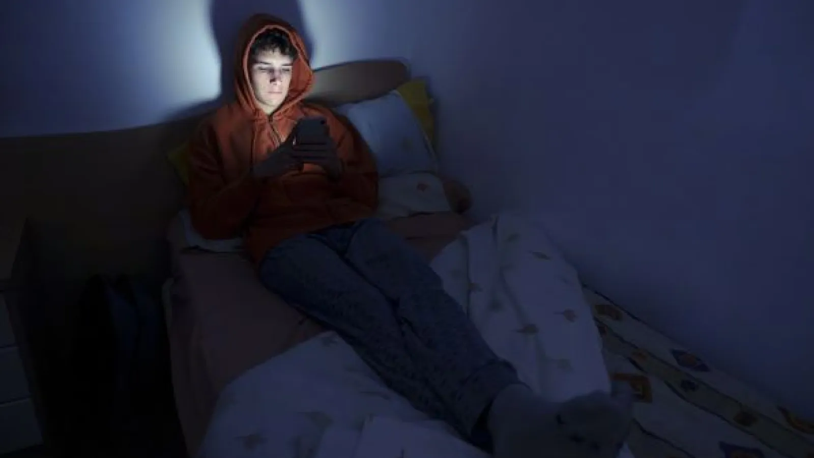 a teen on a smartphone in a dark room