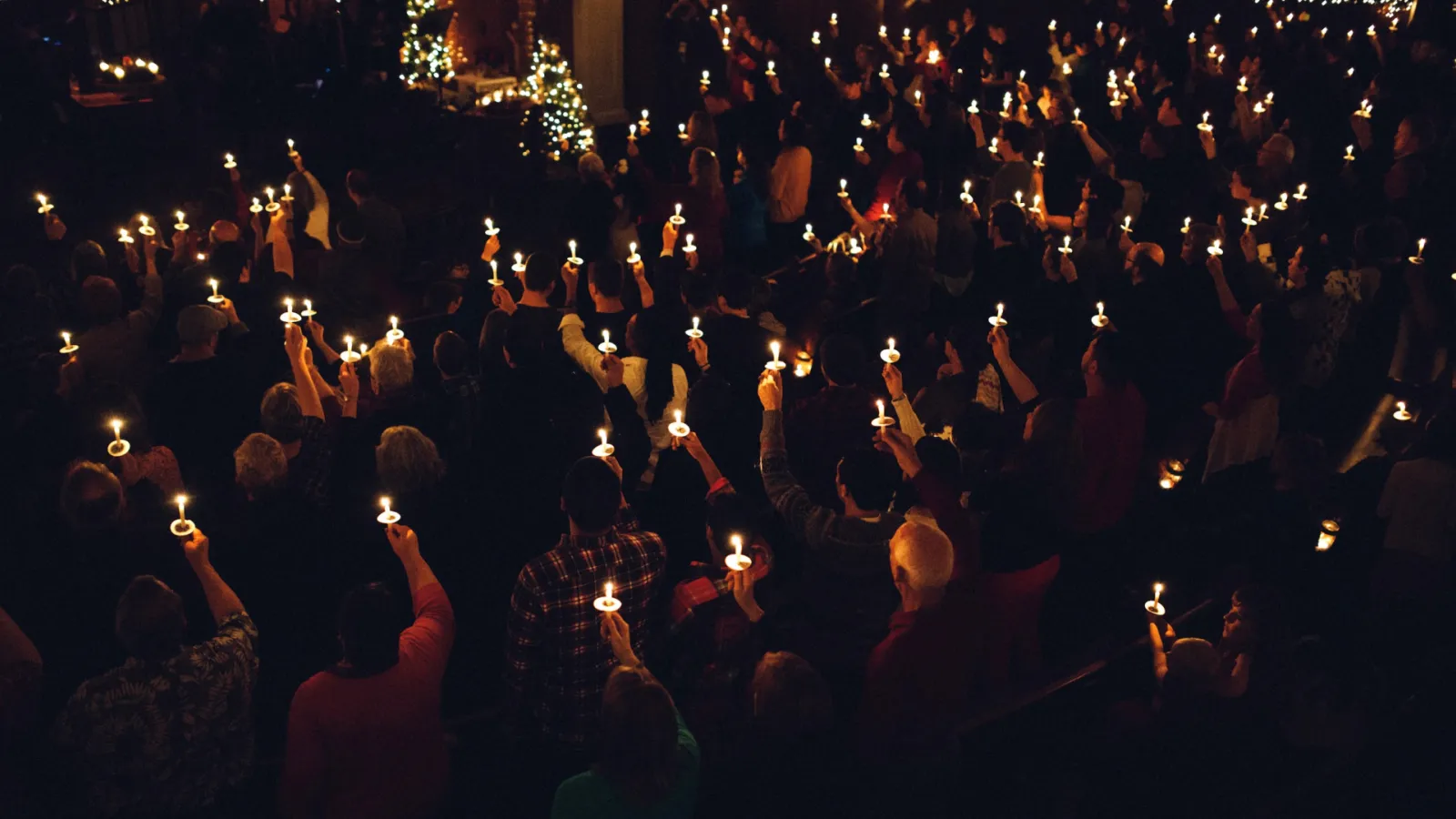 people holding candles at a church service