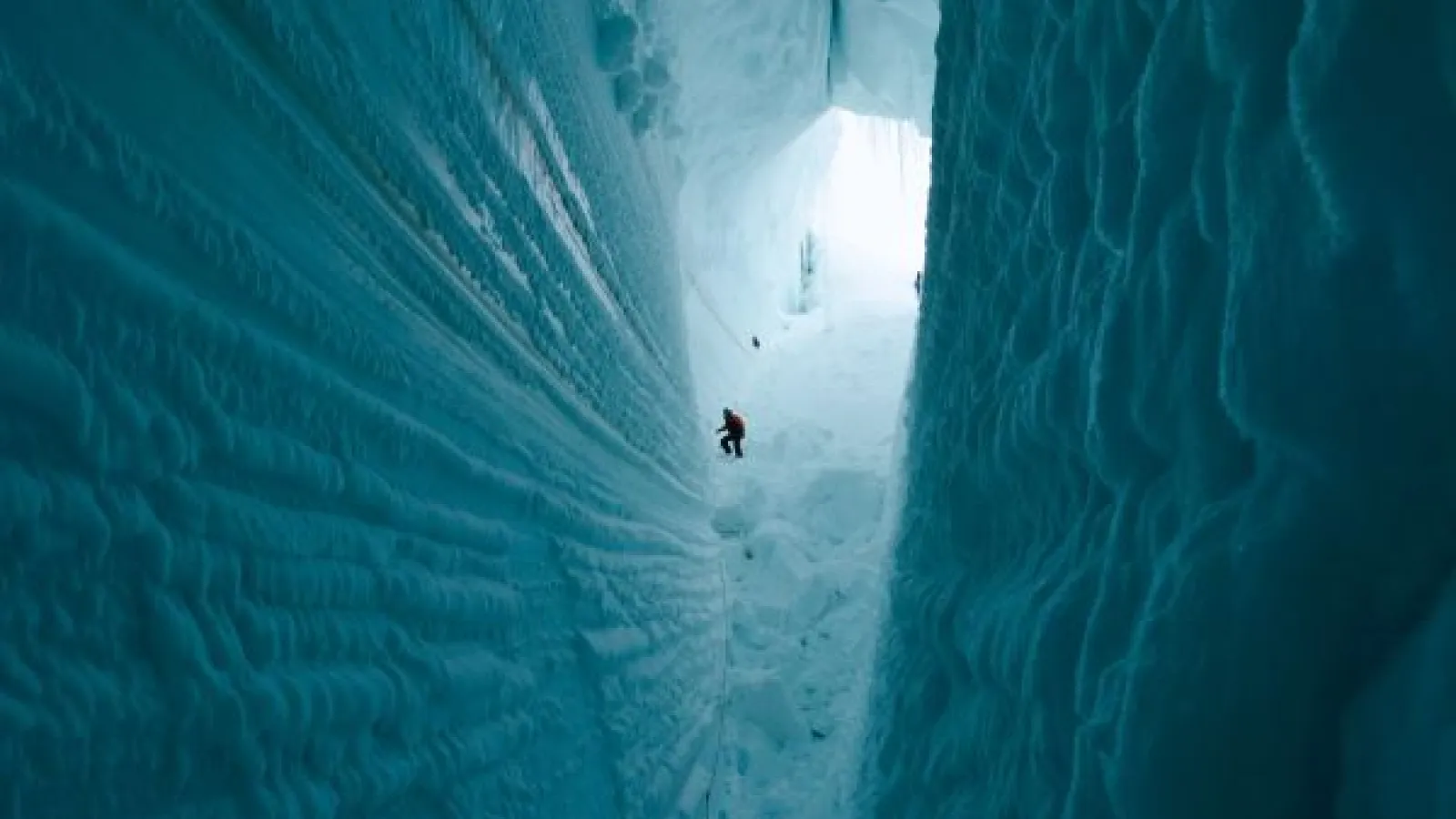 a glacial crevasse, with a very small human shape in the background