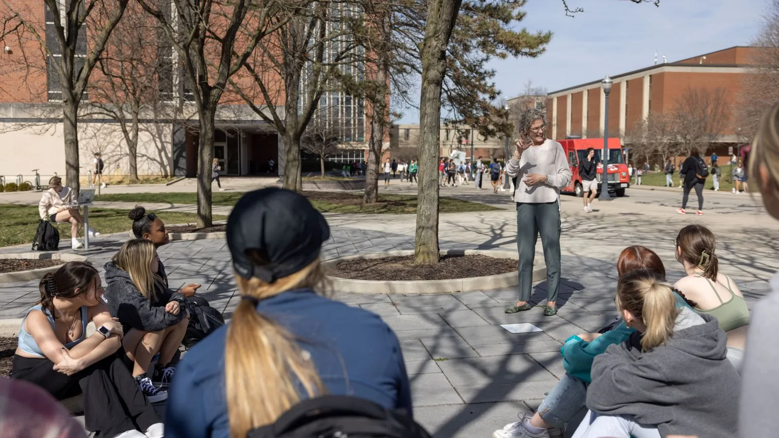 A professor teaching sign language outside on an early Spring day.