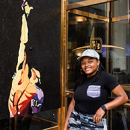 Francesca Miller stands by one of her paintings