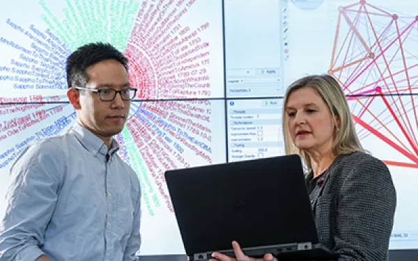 Student and professor discuss project on a projector screen