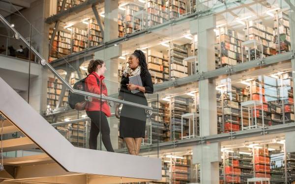 two women talk in front of the stacks in Thompson Library