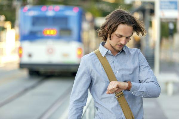 A man looks at his watch at a bus stop