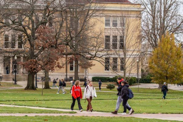 students walk past Mendenhall Lab, a yellow stone building