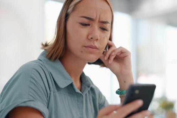 a confused woman looks at her phone