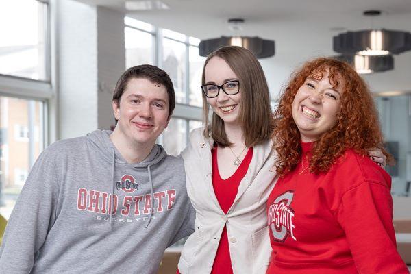 three people smile at the camera