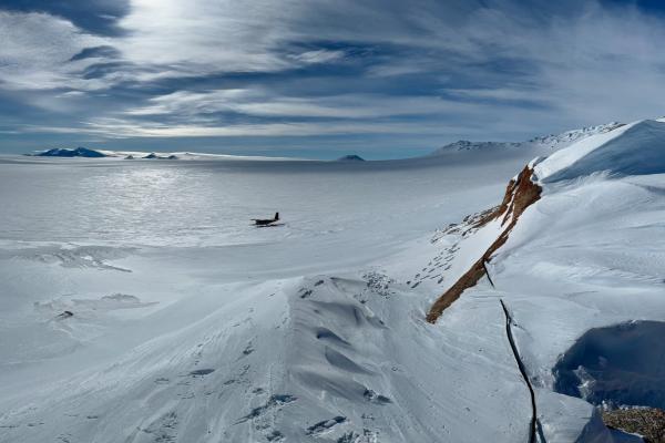 a view from a glacier, overlooking an ice field with a small plane
