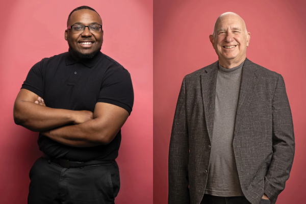 a young black man and an older white man smile at the camera