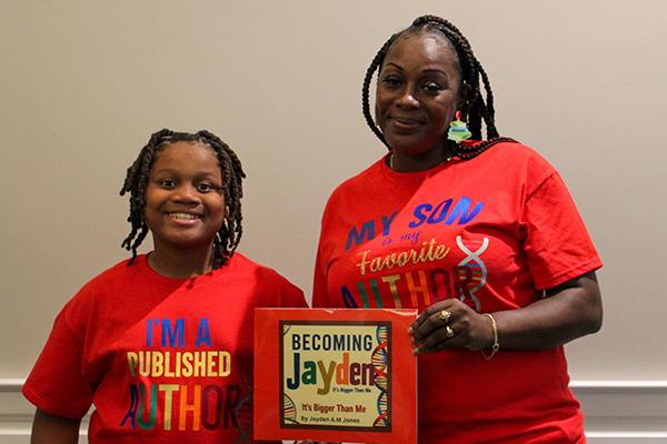 A mother and son pose with the son's published book