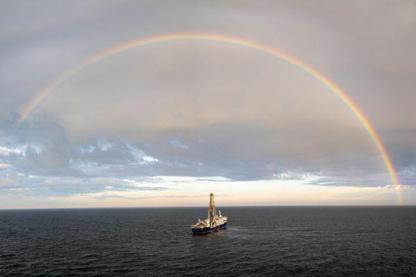 a research ship on the open ocean, below a rainbow