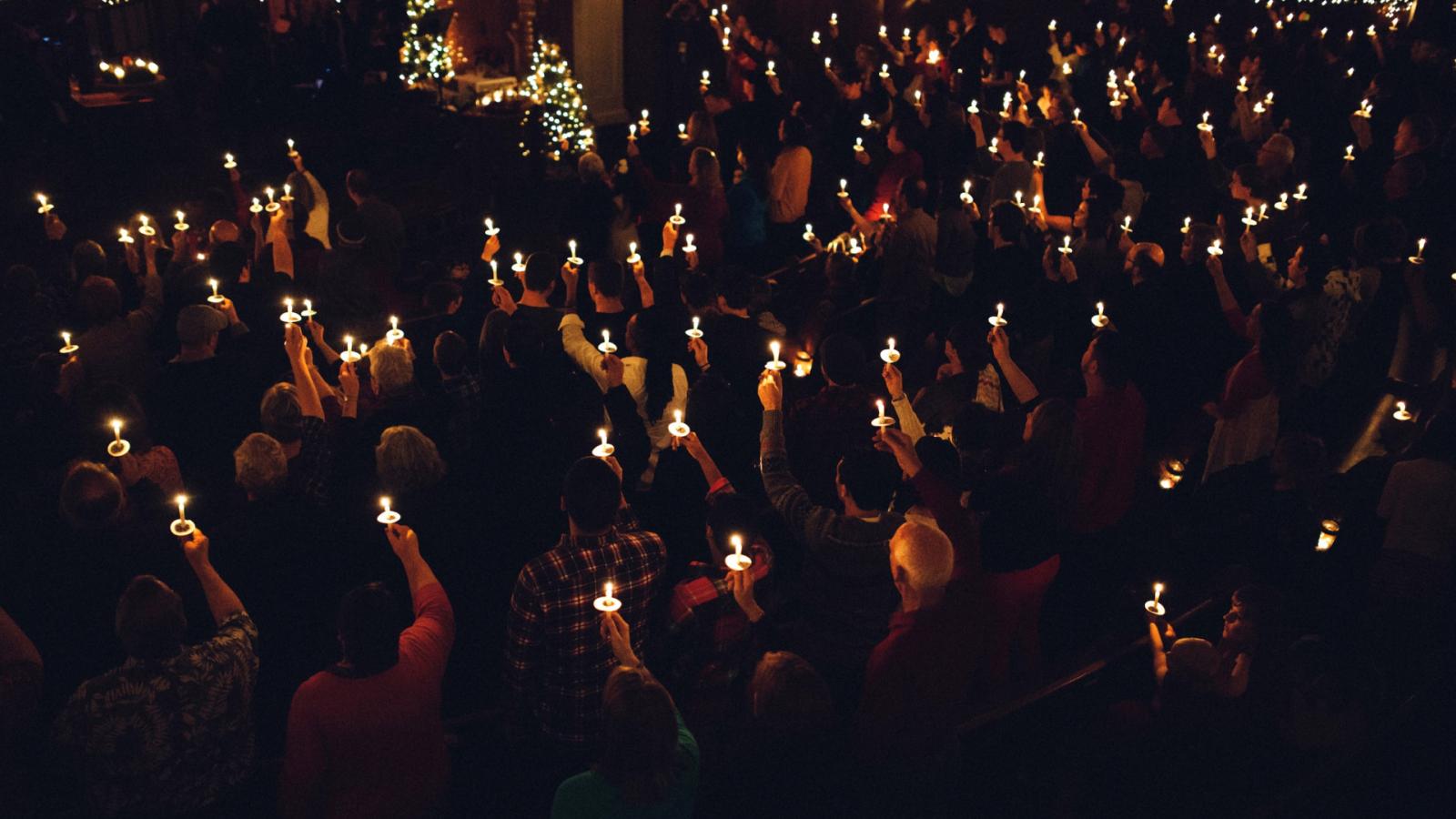 people holding candles at a church service