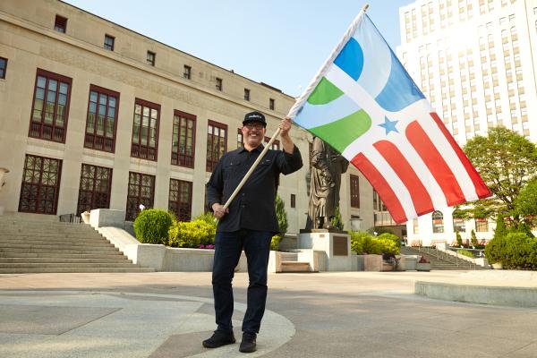 Professor of design Paul Nini waves The People's Flag of Columbus in front of Columbus City Hall. Photo courtesy of Brian Kaiser.