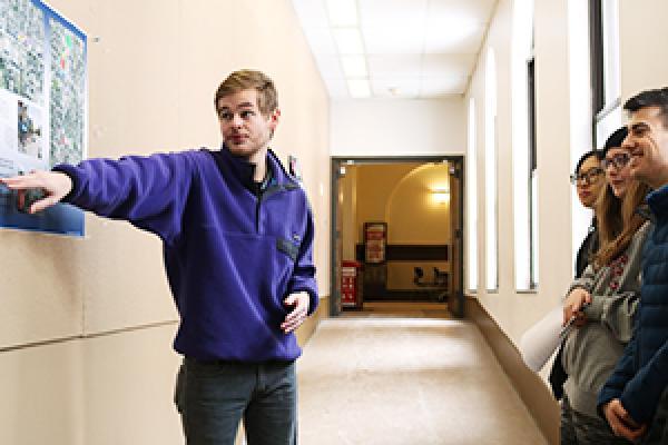 Spencer Gilmore, a fourth-year economics student in Rick Livingston's American Food Cultures class, presents a poster of his to Peter Chan's Visual Design Communications class.